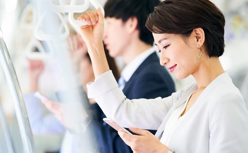 電車通勤中のの人がスマホを見ている写真